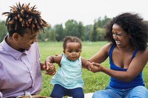 Lycklig afrikansk familj har roligt tillsammans i offentlig parkera - svart far och mor njuter tid med deras dotter - afro människor och förälder enhet begrepp foto