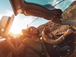 Lycklig ung par håller på med väg resa i tropisk stad - resa människor har roligt körning i trendig konvertibel bil upptäcka ny platser - relation och ungdom semester livsstil begrepp foto