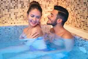 Lycklig ung par håller på med en simning slå samman spa Centrum dag - romantisk älskande har en anbud ögonblick på semester i tillflykt wellness hotell - relation, rekreation, avslappning och kärlek begrepp foto