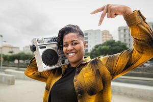 Lycklig afrikansk kvinna har roligt lyssnande till musik med årgång boombox stereo foto