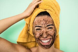 ung leende kvinna applicering kaffe skrubba mask på ansikte - Lycklig flicka har hud vård spa dag på Hem - friska alternativ naturlig exfoliering behandling och ungdom människor livsstil begrepp foto