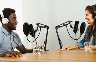 Lycklig raser vänner inspelning en podcast - man och kvinna har roligt arbetssätt tillsammans foto