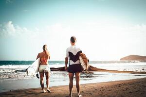 par av surfare stående på de strand med surfingbrädor framställning till surfa på hög vågor - sportig ung människor har roligt under en surfing dag - extrem sporter, relation och ungdom livsstil begrepp foto