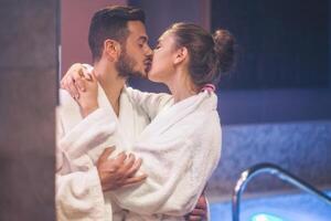 passionerad ung par kissing under en simning slå samman spa Centrum dag - romantisk älskande har en anbud ögonblick på semester i tillflykt wellness hotell - begrepp av människor relation, koppla av och kärlek foto