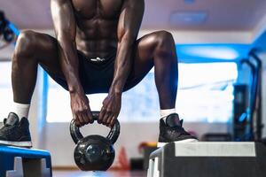 ung afrikansk man Träning inuti Gym - passa manlig håller på med kettle övning träna session i sport klubb Centrum - kondition och bodybuilding livsstil begrepp foto