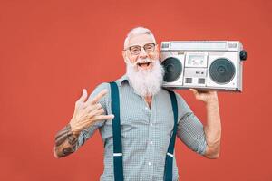 Lycklig senior man lyssnande till musik med boombox utomhus- - galen hipster manlig har roligt dans med årgång stereo - begrepp av äldre människor livsstil foto