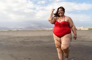 Lycklig plus storlek kvinna har roligt gående på de strand - kurvig självsäker människor livsstil begrepp foto