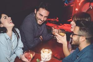 Lycklig vänner har roligt i cocktail jazz bar - ung tusenåriga människor dricka ad skrattande tillsammans i nattklubb - nattliv underhållning och ungdom kultur livsstil högtider begrepp foto