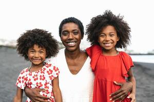 Lycklig afrikansk familj har roligt på de strand under sommar högtider - porträtt av afro människor njuter semester dagar - föräldrar kärlek och resa livsstil begrepp foto