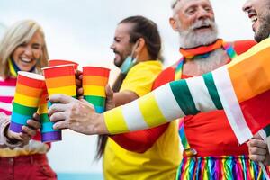 Lycklig människor med annorlunda ålder glädjande och dricka cocktails i Gay stolthet festival under korona virus utbrott foto