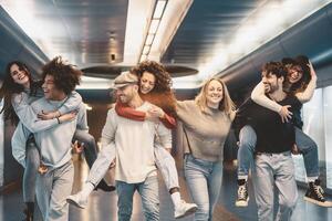 grupp ung vänner har roligt piggybacking i underjordisk storstads tunnelbana - Lycklig trendig människor njuter nattliv och skrattande tillsammans - ungdom tusenåriga vänskap livsstil begrepp foto