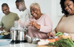 Lycklig svart familj har roligt matlagning tillsammans i modern kök - mat och föräldrar enhet begrepp foto