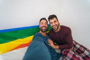Lycklig Gay par har roligt tar selfie i säng - homosexuell kärlek och teknologi begrepp foto