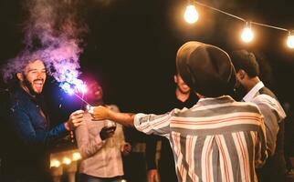 Lycklig ung vänner fira ny år eve med sparklers fyrverkeri och dricka vin på Hem terrass - ungdom människor livsstil och högtider begrepp foto