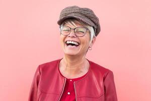 Lycklig senior kvinna har roligt utomhus- - trendig mogna person skrattande och njuter pensionerad tid - äldre människor livsstil och mors dag begrepp - korall bakgrund foto