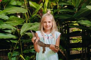 sommar porträtt av en Lycklig liten flicka på de ö av mauritius med en crocodile.girl på de Zoo med en krokodil i henne vapen foto