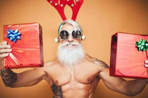 Lycklig passa senior innehav jul presenterar - hipster äldre man har roligt ger gåva låda under xmas högtider - äldre trendig människor och traditionell livsstil kultur begrepp foto