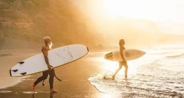 Lycklig vänner med annorlunda ålder surfing tillsammans på tropisk hav - sportig människor har roligt under semester surfa dag - äldre och ungdom människor sport livsstil begrepp foto