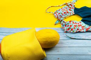 topp se av en baddräkt och en melon i en väska, liggande på en blå trä- och gul bakgrund.sommar semester begrepp foto