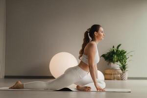 en flicka i vit kläder gör yoga på en matta inomhus foto