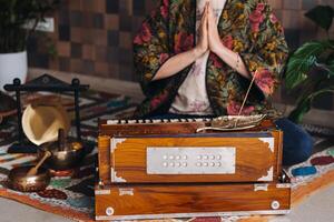 händer av en kvinna Sammanträde på de golv och spelar de harmonium under de öva av kundalini yoga foto