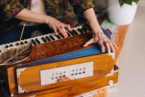 händer av en kvinna Sammanträde på de golv och spelar de harmonium under de öva av kundalini yoga foto