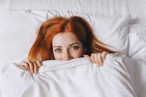 coy ung kvinna dölja under säng omslag foto