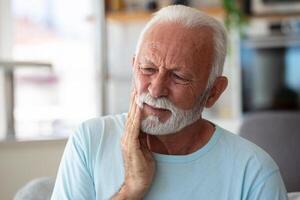 tand smärta och tandvård. senior man lidande från fruktansvärd stark tänder smärta, rörande kind med hand. känsla smärtsam tandvärk. dental vård och hälsa begrepp. foto