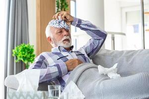 mogna man känsla sjuk med kall och feber på Hem, sjuk med influensa sjukdom Sammanträde på de soffa med is packa på hans huvud foto