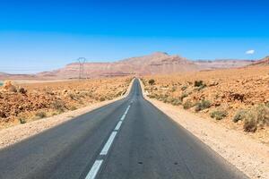 ändlös väg i sahara öken- med blå himmel, marocko afrika foto