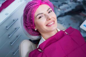 ung kvinna patient med Söt leende granskning dental inspektion på tandläkare klinik. friska tänder och medicin, stomatologi begrepp foto