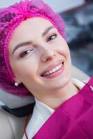 ung kvinna patient med Söt leende granskning dental inspektion på tandläkare klinik. friska tänder och medicin, stomatologi begrepp foto