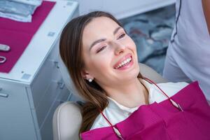 ung kvinna patient med Söt leende granskning dental inspektion på tandläkare klinik. friska tänder och medicin, stomatologi begrepp foto