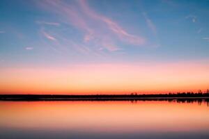 lugn vattnen en lycksalig reflexion av en skön pastell sjö och himmel, var lugn möter naturens palett, skapande en harmonisk oas av mjuk nyanser och eterisk skönhet foto