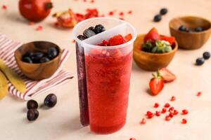 jordgubb och blåbär juice med granatäpple frön eras i dubbel- sida kopp isolerat på tabell topp se av friska morgon- dryck foto
