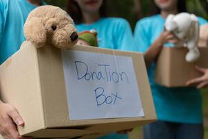 Lycklig ung asiatisk studenter olika volontärer håll donera låda och leksaker för välgörenhet till dela med sig barn och barnhem, en välgörenhet för hållbarhet. volontär- arbete livsstil och social samarbete foto