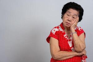 deprimerad asiatisk senior kvinna ensam besviken och tappa bort minne i isolerat vit bakgrund. porträtt gammal kvinna sjuk sjuk depression sjukdom känna ledsen och olycklig, demens, hälsa problem begrepp. foto