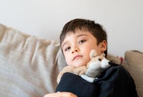 unge pojke Sammanträde på soffa, nära upp uppriktig porträtt söt skola tittar på TV på helg.positiv barn avkopplande på Hem efter skola foto