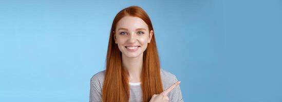 trevlig karismatisk hjälpsam vänligt utseende kvinna rödhårig blå ögon pekande vänster index finger hjälp göra beslut plocka produkt Lagra leende brett självsäker blick kamera be förtroende henne foto