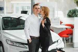 ung skön Lycklig par uppköp en bil. Make uppköp bil för hans fru i en salong. bil handla begrepp foto