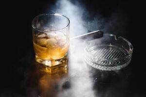 glas av kall whisky med cigarr på mörk bakgrund foto