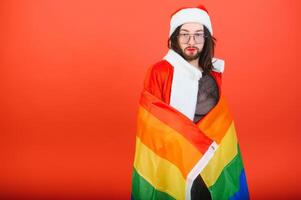 Gay man klädd som santa claus innehav en flerfärgad flagga foto