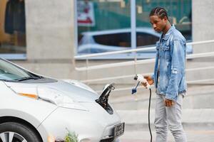 afrikansk amerikan man laddning hans elektrisk bil. foto