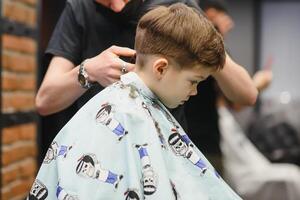 glad caucasian pojke få frisyr i frisör foto