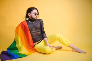 Gay man håll regnbåge randig flagga isolerat på färgad bakgrund studio porträtt. människor livsstil mode lgbtq begrepp foto