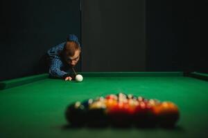 ung stilig man lutande över de tabell medan spelar snooker foto