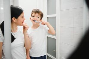 söt mor undervisning unge pojke tänder pensling foto