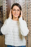 flicka handla för glasögon på försäljning säsong i optisk Lagra. eleganta kund uppköp många glasögon på rabatt. foto