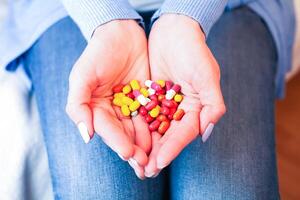 kvinna innehar många flerfärgad piller i händer. tar vitaminer, kosttillskott, antibiotikum, antidepressivt medel och smärtstillande medicin. närbild. foto