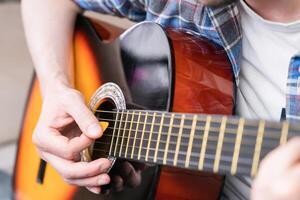 händer av en ung man med medlare spelar på gitarr strängar. närbild. selektiv fokus. foto